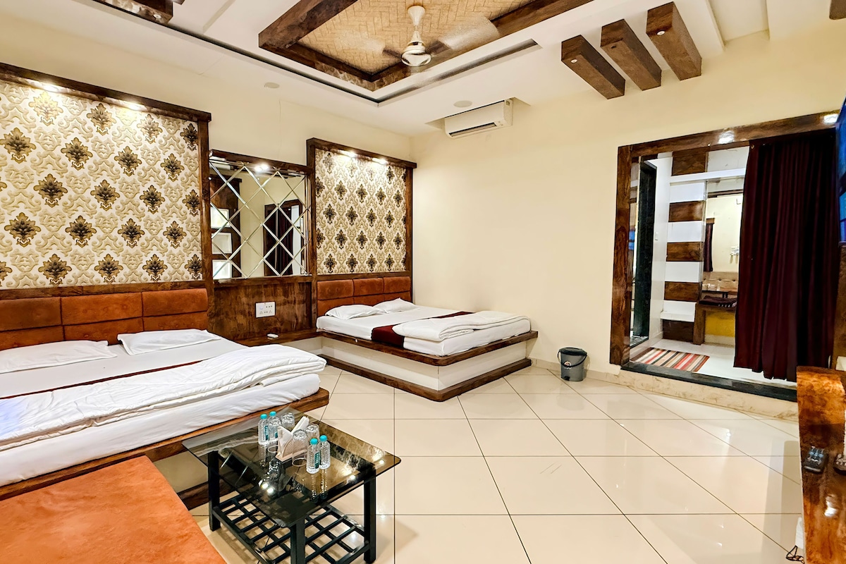 A hotel room with two beds, a small table, a mirror, and a view of the outside.