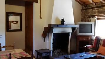 Ein gemütliches Wohnzimmer mit Kamin, Holzmöbeln und einem Fernseher.