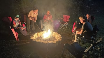 Un gruppo di persone sedute attorno a un fuoco da campo in un ambiente all'aperto.