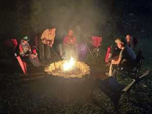 Un grupo de personas sentadas alrededor de una fogata en un entorno al aire libre.