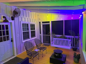 Eine überdachte Veranda mit zwei Stühlen, einem Tisch und einem Ventilator.