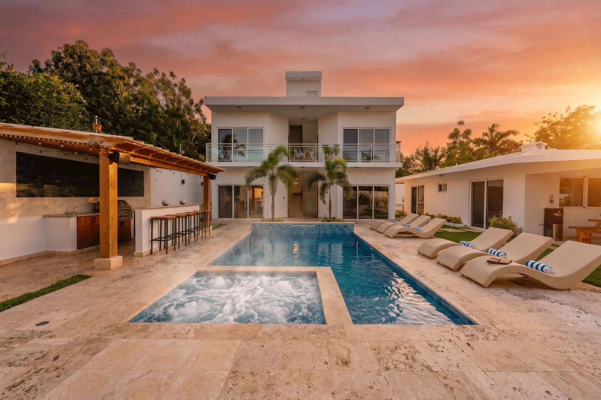 A two-story house with a swimming pool, outdoor bar, and lounge chairs.