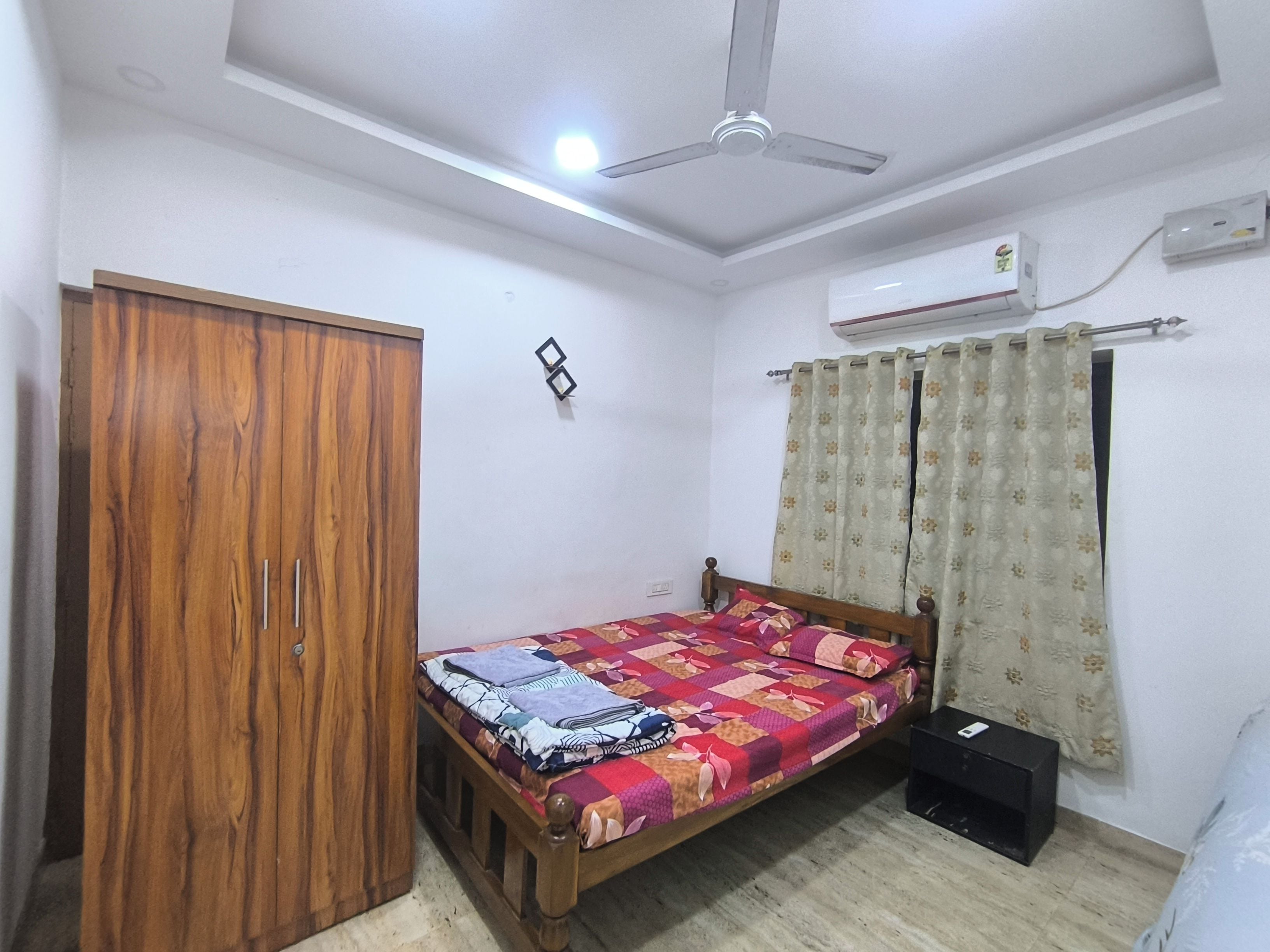 Une chambre avec un lit simple, une armoire, un climatiseur et un ventilateur de plafond.