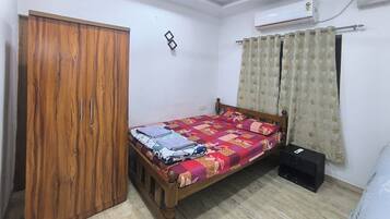 Une chambre avec un lit simple, une armoire, un climatiseur et un ventilateur de plafond.