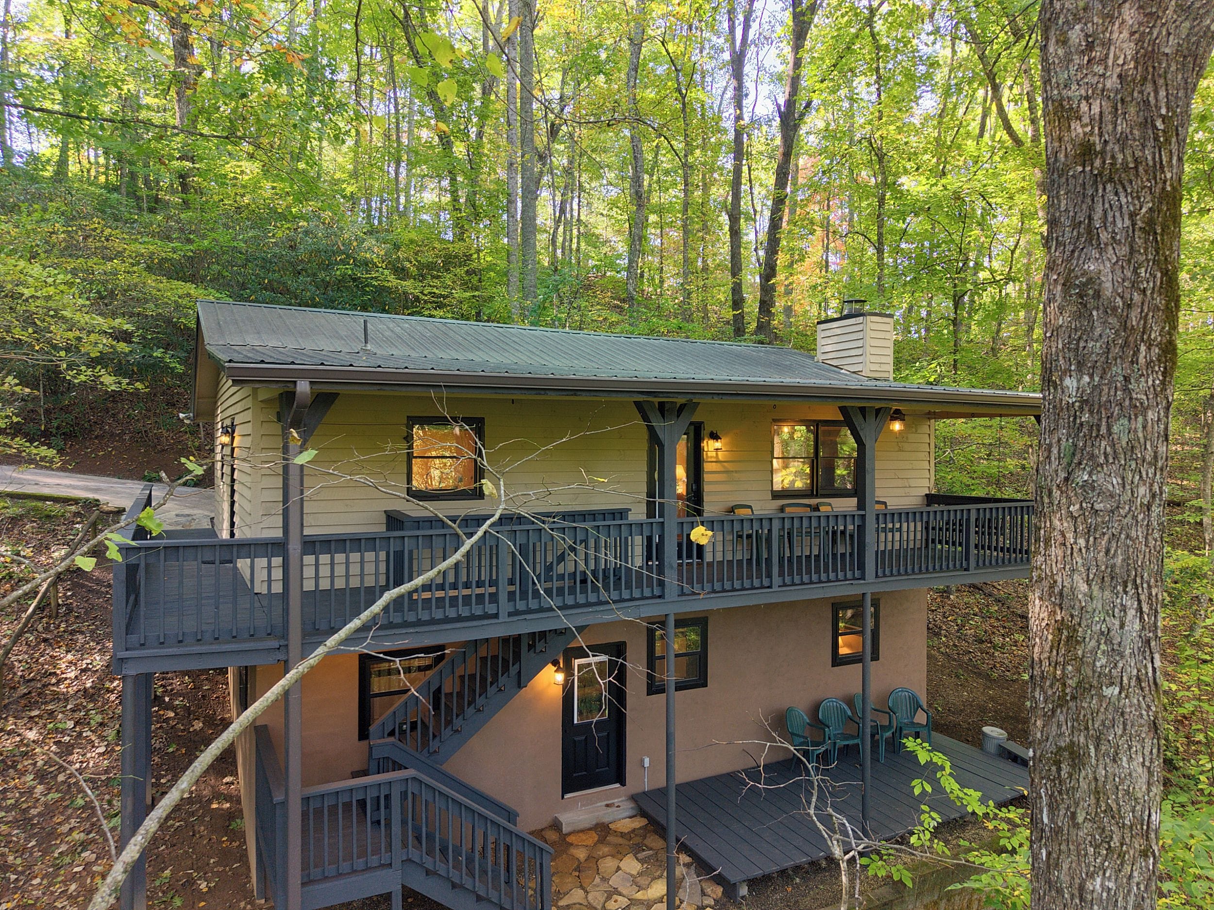 A two-story cabin with a balcony, a staircase, and outdoor seating.