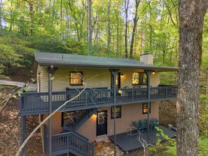 Une cabane à deux étages dotée d’un balcon, d’un escalier et d’un espace salon extérieur.