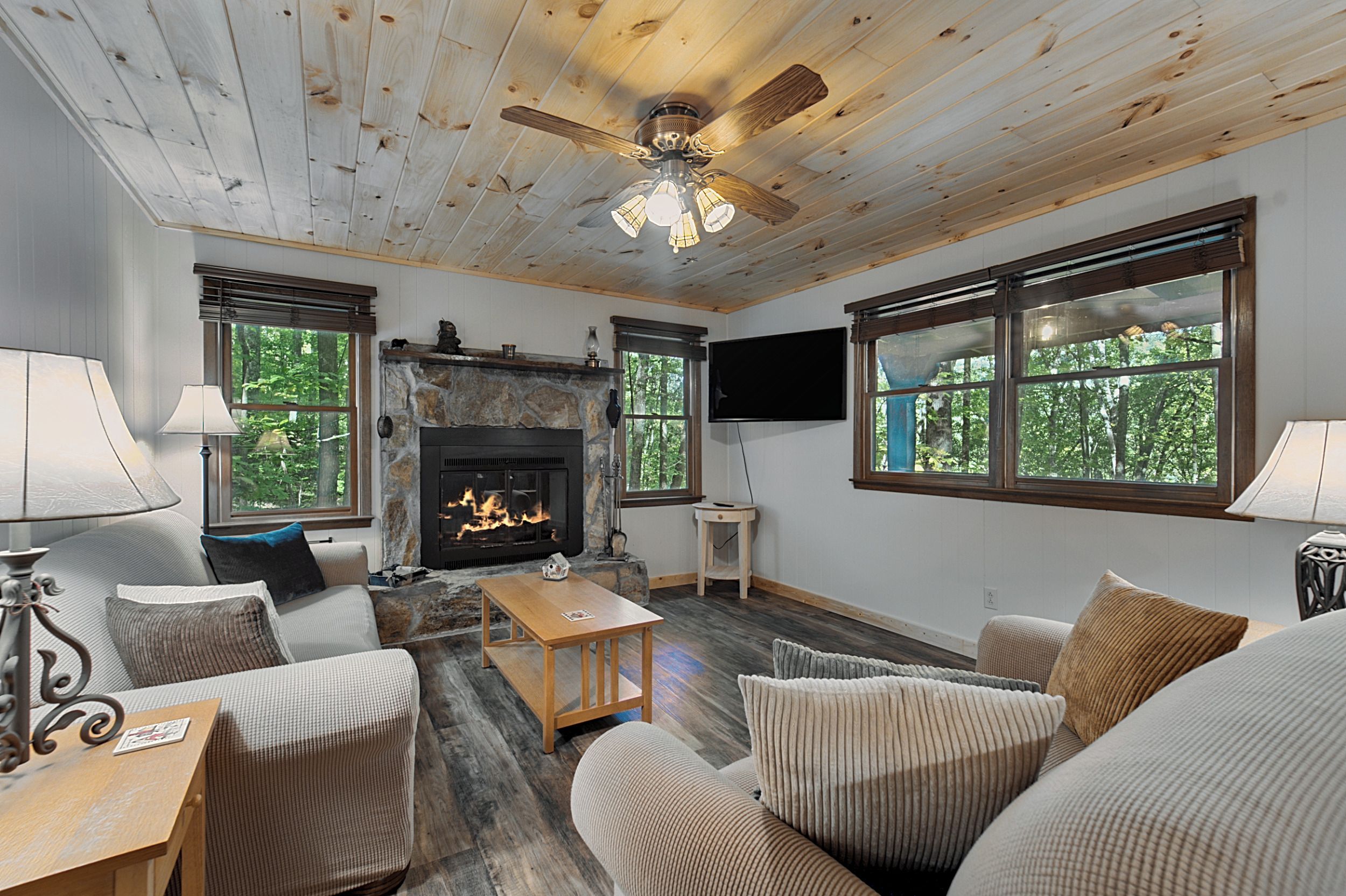 Ein gemütliches Wohnzimmer mit Kamin, Holzböden und großen Fenstern.