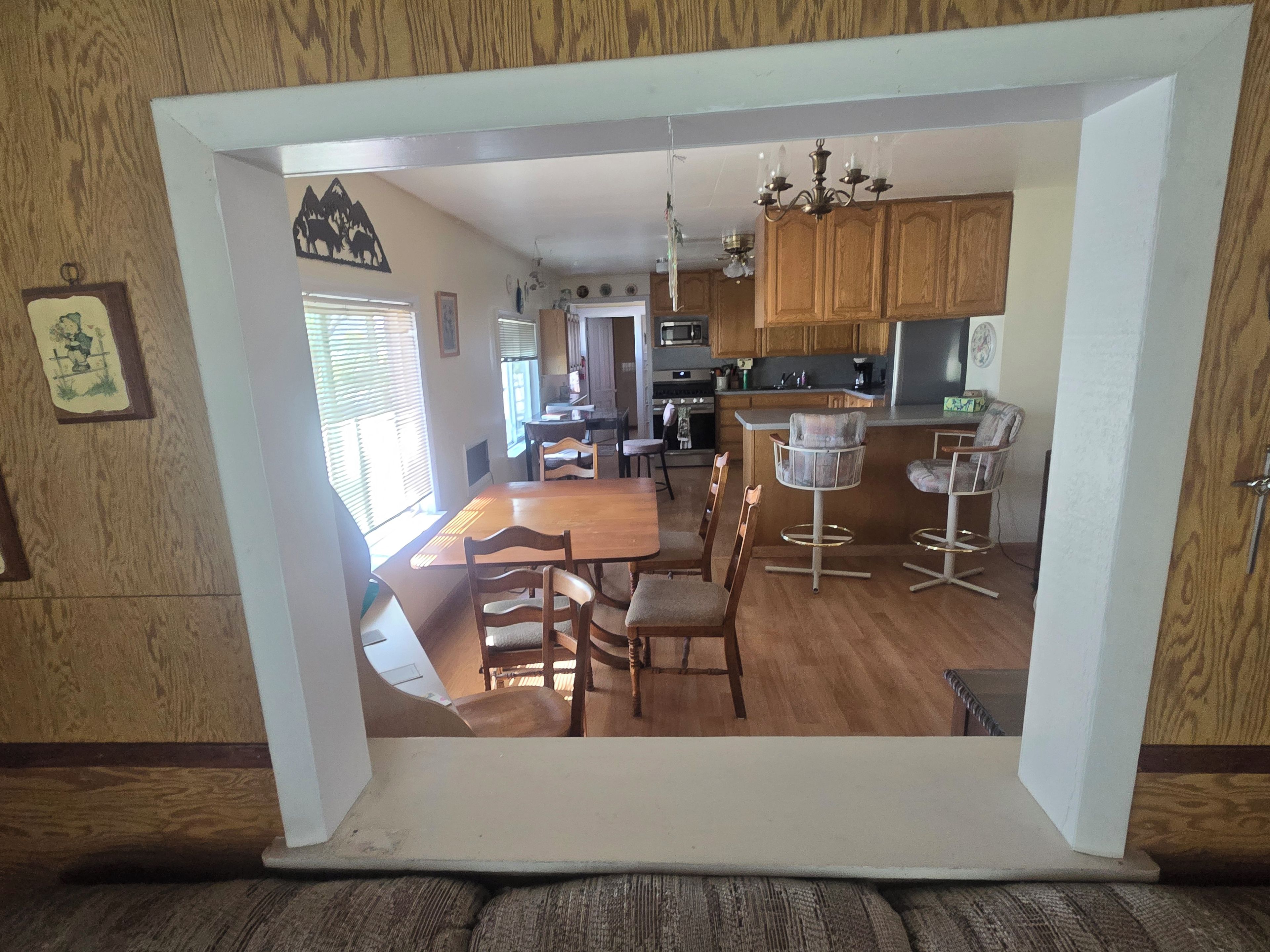 A dining area with a wooden table and chairs, a kitchen with wooden cabinets, and a bar area with stools.