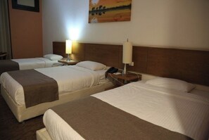 A hotel room with two beds, each with a bedside table, a lamp, and a painting on the wall. - El Eman Hotel (Ar Radiseyah Bahri Edfu)