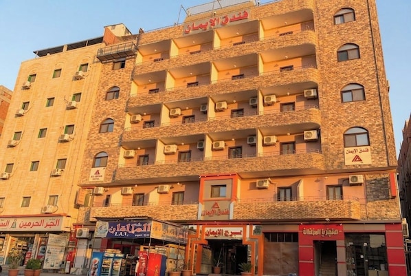 A multi-story building with balconies, air conditioning units, and signage in Arabic. - El Eman Hotel (Ar Radiseyah Bahri Edfu)