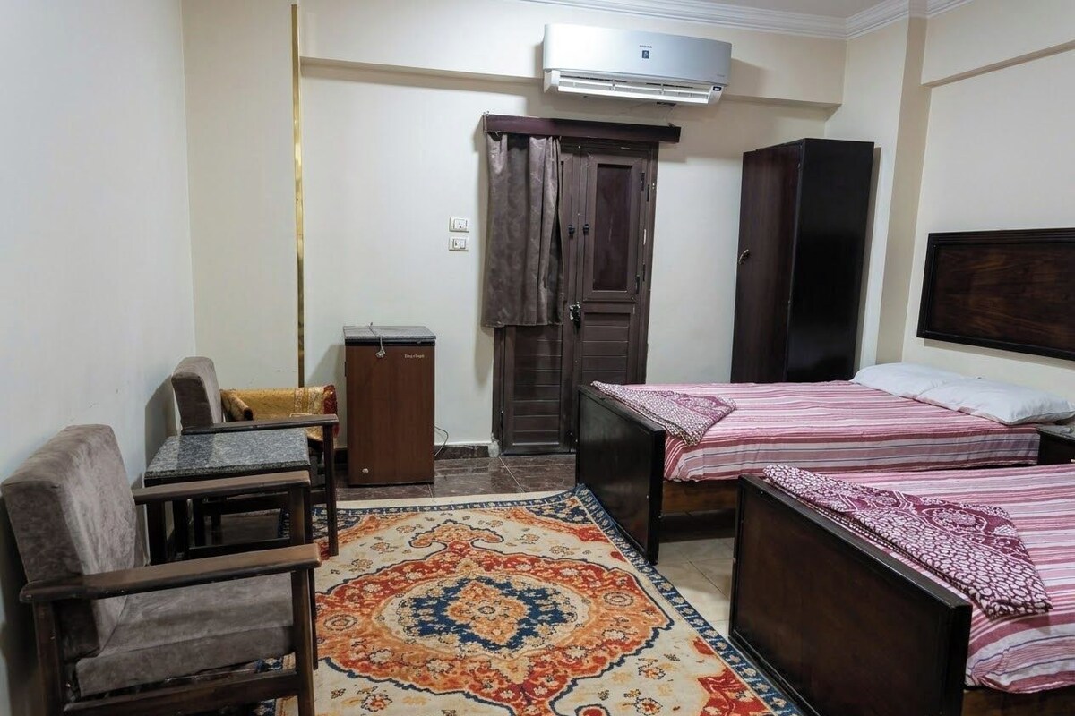 A small room with a bed, a sofa, a desk, and a wardrobe.