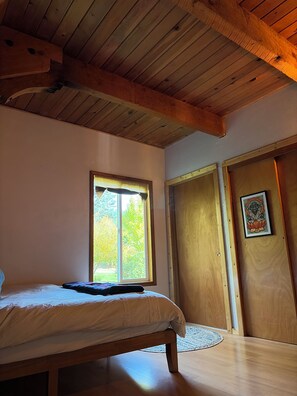 Une chambre à coucher avec un plafond en bois, un lit, une fenêtre et une porte.