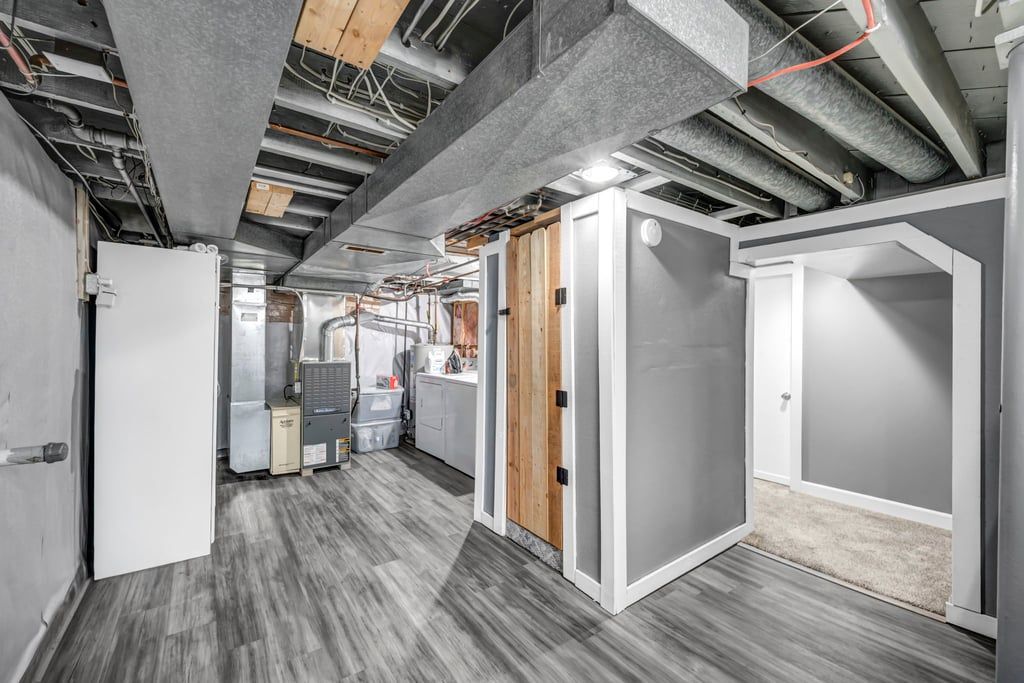 A modern kitchen with stainless steel appliances, a wooden door, and a grey floor.