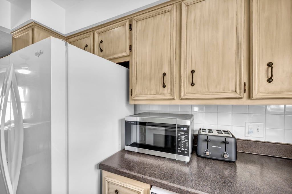 A kitchen with a white refrigerator, a microwave, and a toaster on the countertop.