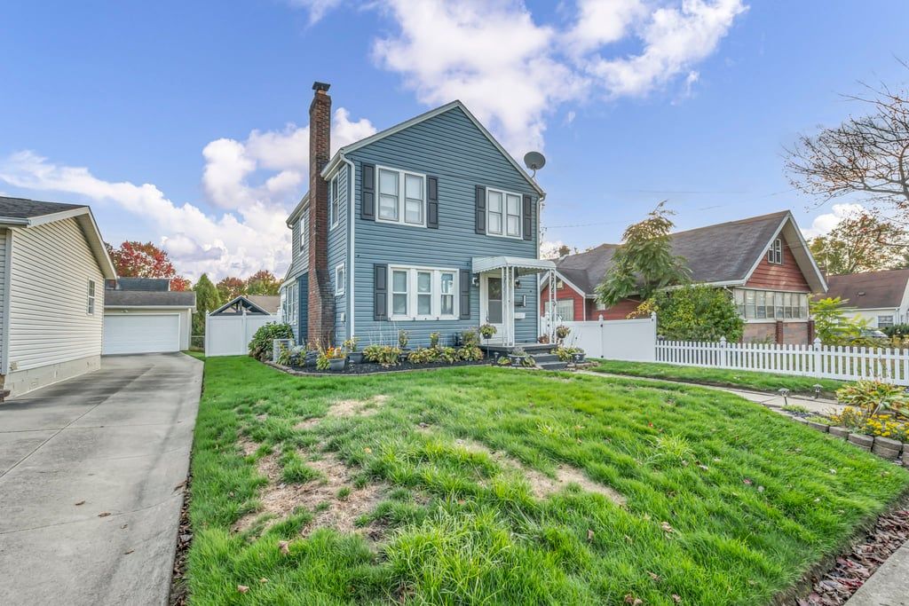 A two-story house with a front yard and a white picket fence.