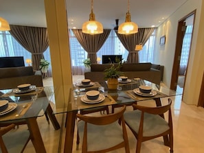 Un comedor con mesa de vidrio, sillas de madera y una planta en el centro.