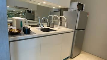 A modern kitchen with a built-in sink, stainless steel appliances, and a microwave on top of the refrigerator.