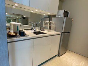 Een moderne keuken met een ingebouwd spoelgedeelte, roestvrijstalen apparatuur en een magnetron boven de koelkast.