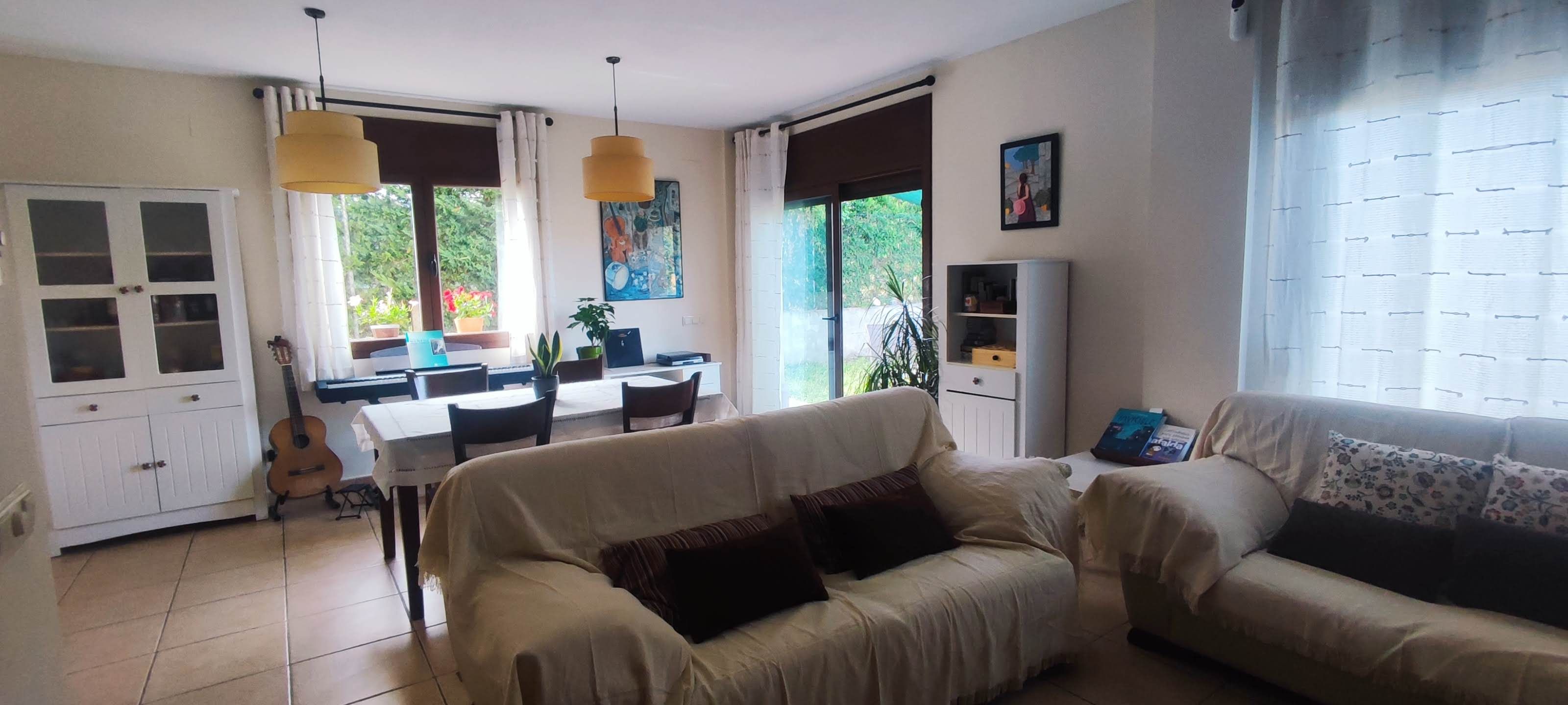 Un salon avec un canapé, une table à manger et des chaises, une guitare et un meuble pour la télévision.