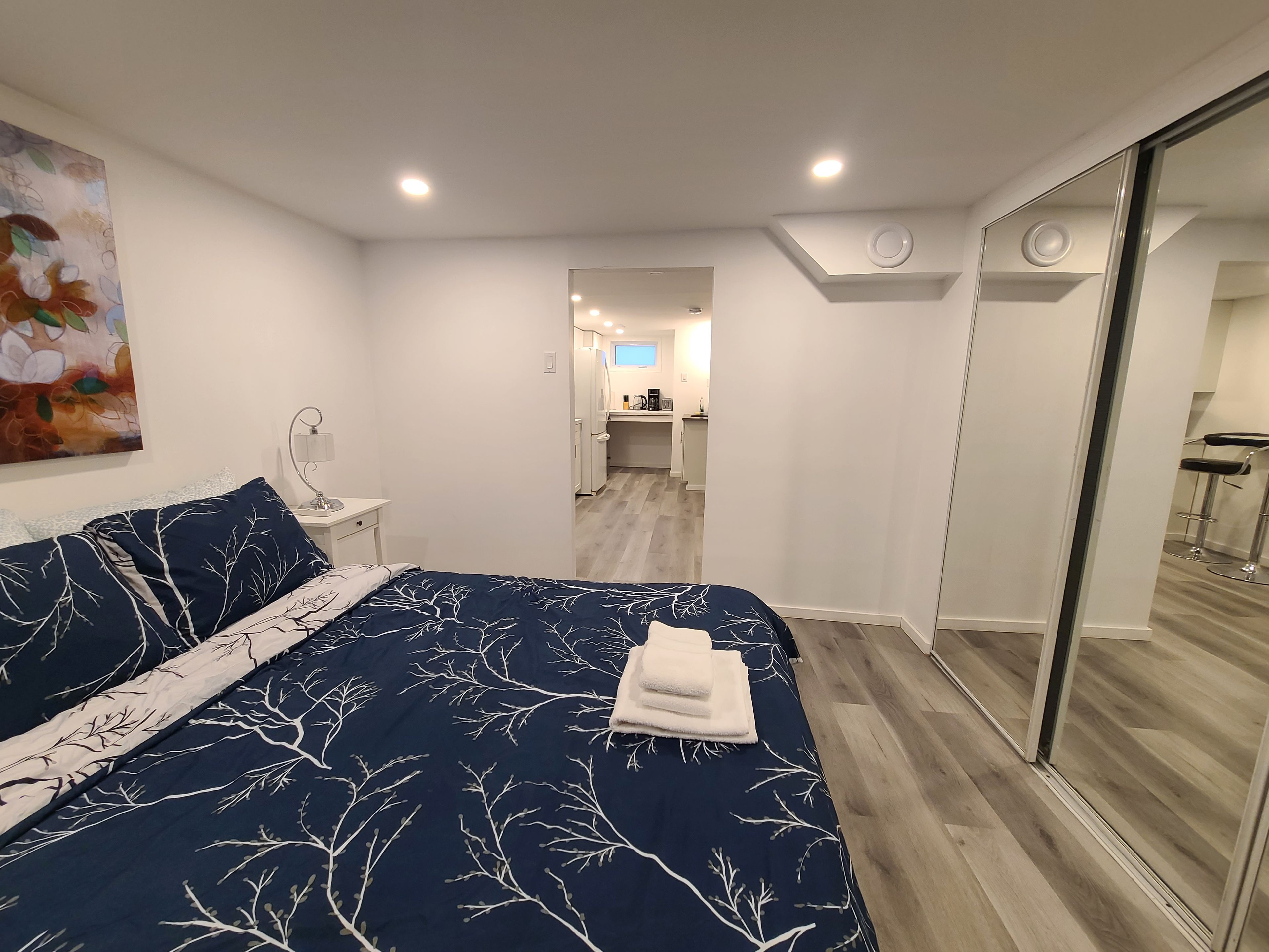 Un dormitorio con una cama grande, una mesita de noche, una lámpara de pared y un cuadro.