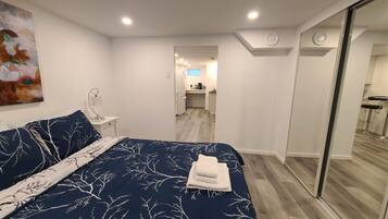 Un dormitorio con una cama grande, una mesita de noche, una lámpara de pared y un cuadro.