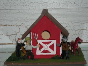 Una escena en miniatura con un granero rojo, un horcón y figuras de un hombre, un caballo y un personaje con casco.