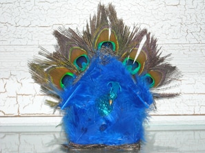Un couvre-chef orné d’une tête de paon, avec une base bleue et des plumes aux couleurs vives.