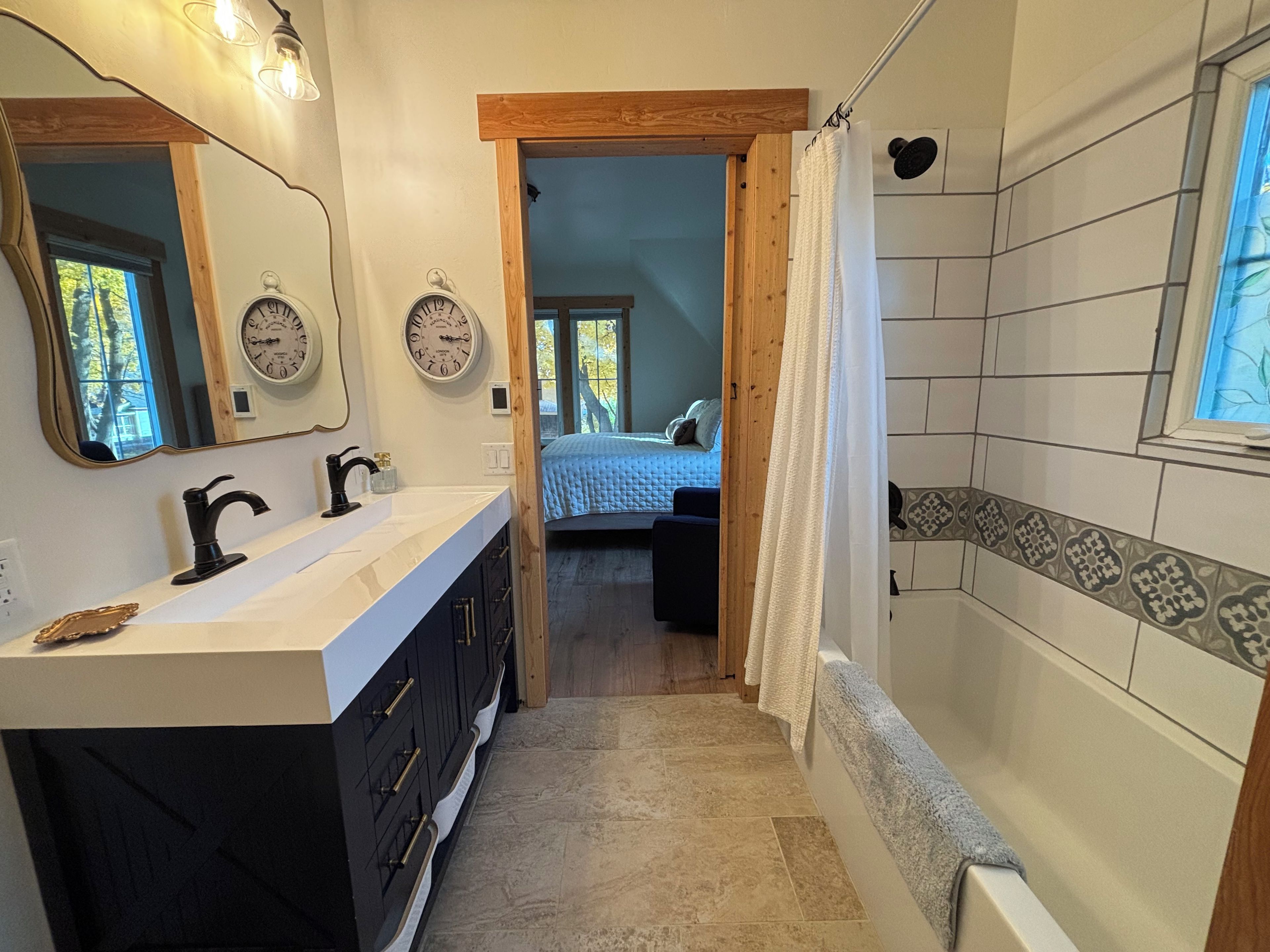Un bagno con un mobile lavabo, uno specchio, un orologio e una zona doccia.