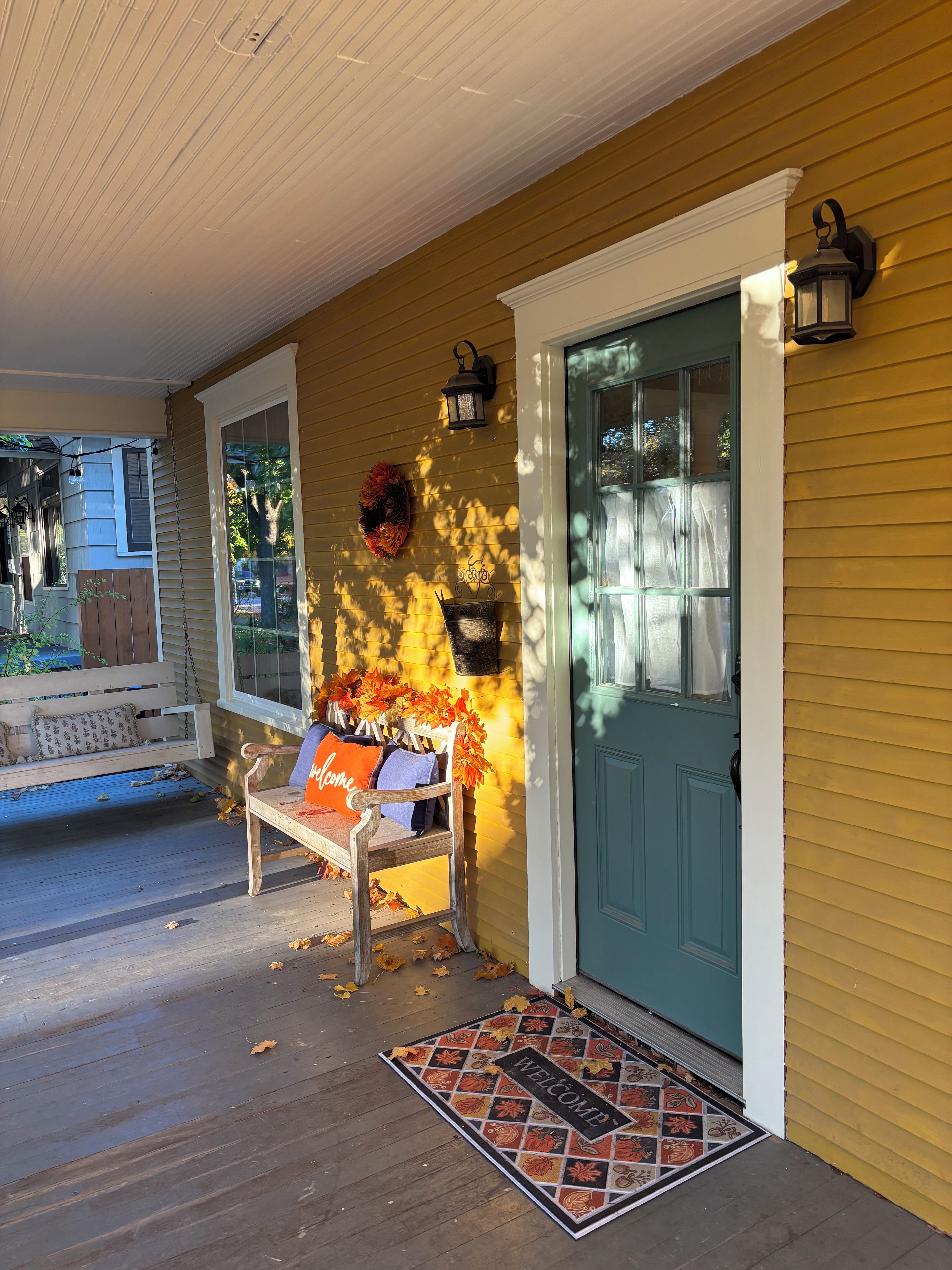 A porch with a bench, a welcome mat, and a door.