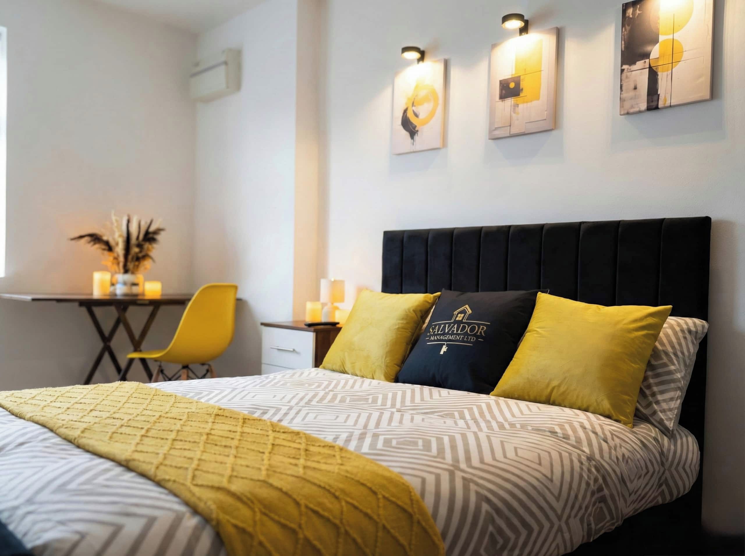 Una camera d'albergo con un letto, un comodino, una sedia e un'opera d'arte appesa al muro.