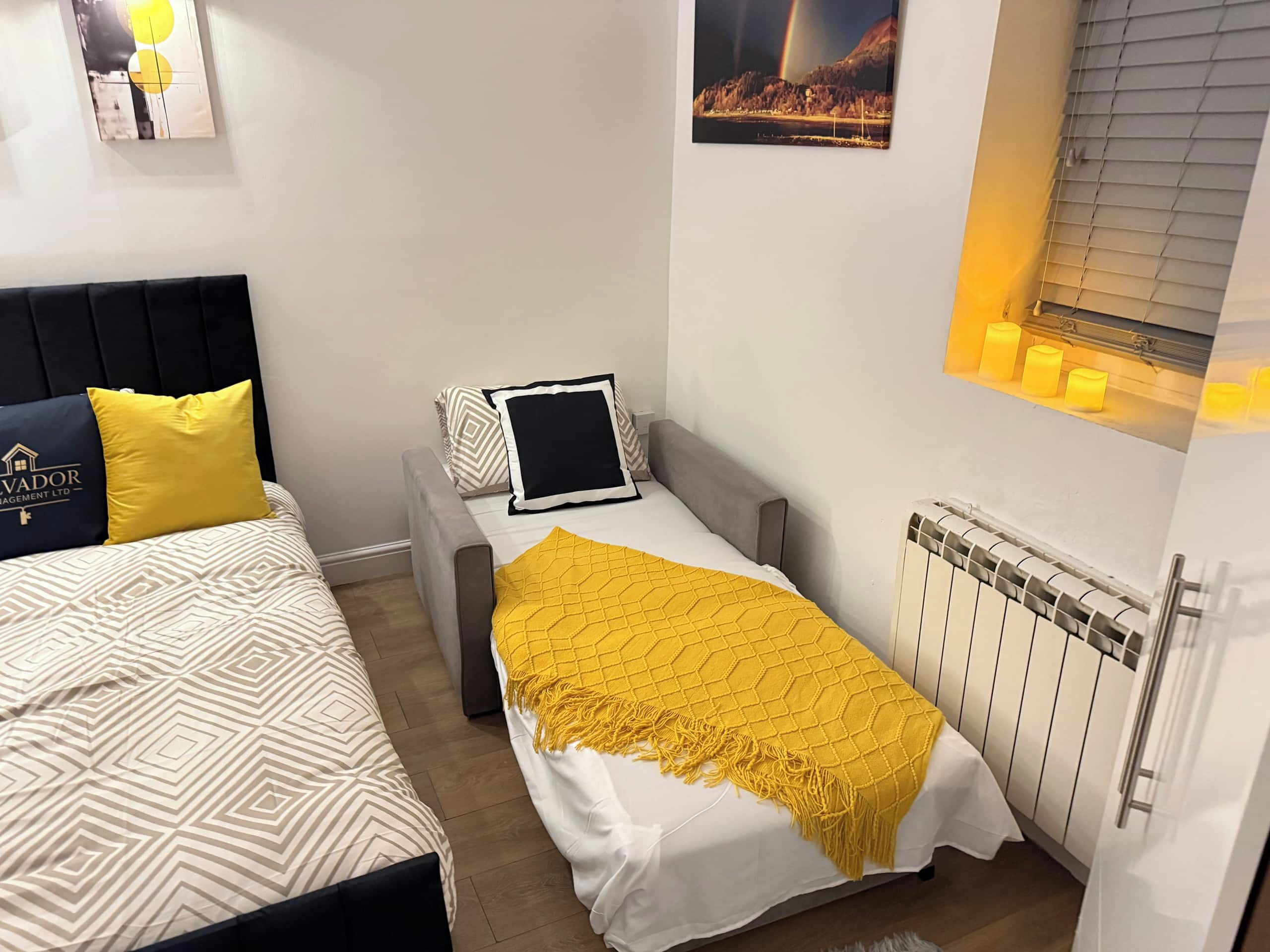 Un dormitorio con cama, mesita de noche, lámpara y ventana con cortinas.