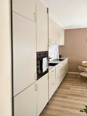 A modern kitchen with white cabinets, a black oven, and a marble backsplash. - Bright flat in Storo with balcony (Oslo)