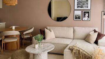 A modern living room with a sofa, round coffee table, and a dining area with chairs.