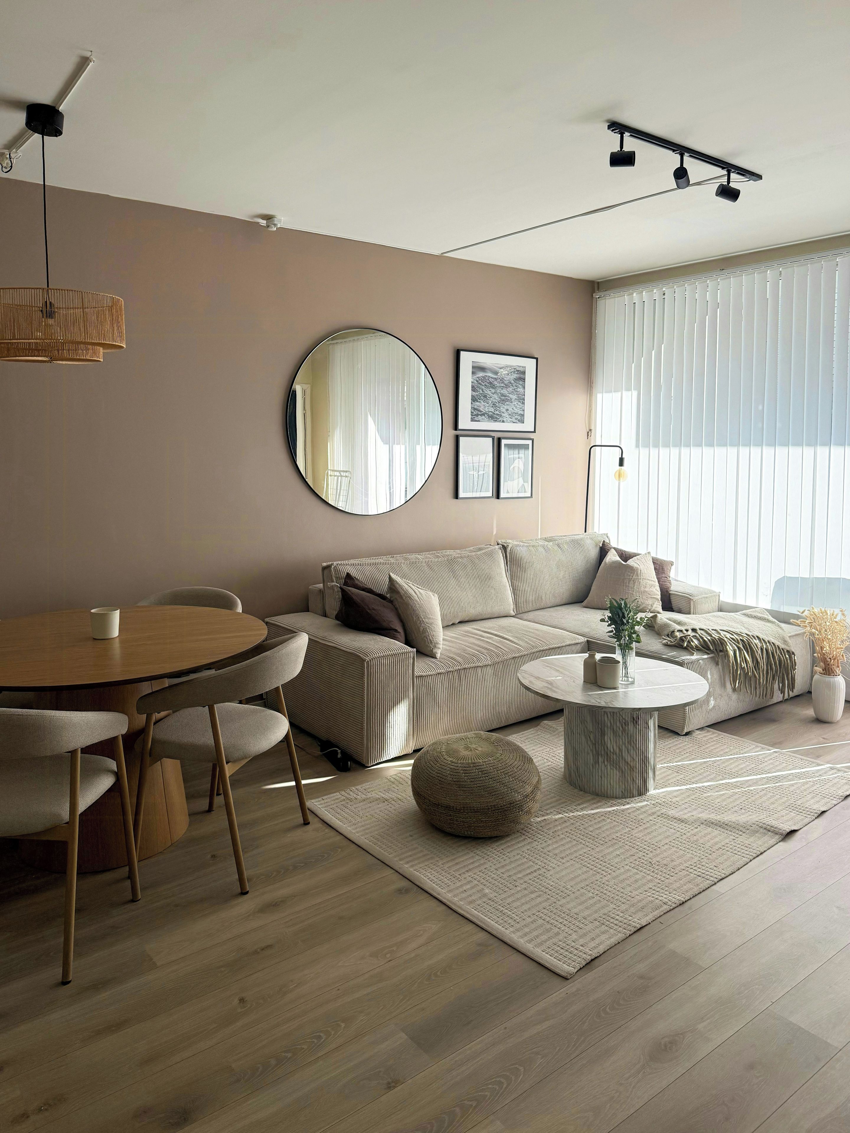 A modern living room with a sofa, round coffee table, and a dining table with chairs.