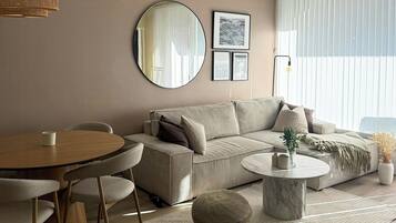 A modern living room with a sofa, round coffee table, and a dining table with chairs.
