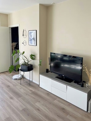 A modern living room with a flat-screen TV, a potted plant, and a minimalist design. - Bright flat in Storo with balcony (Oslo)