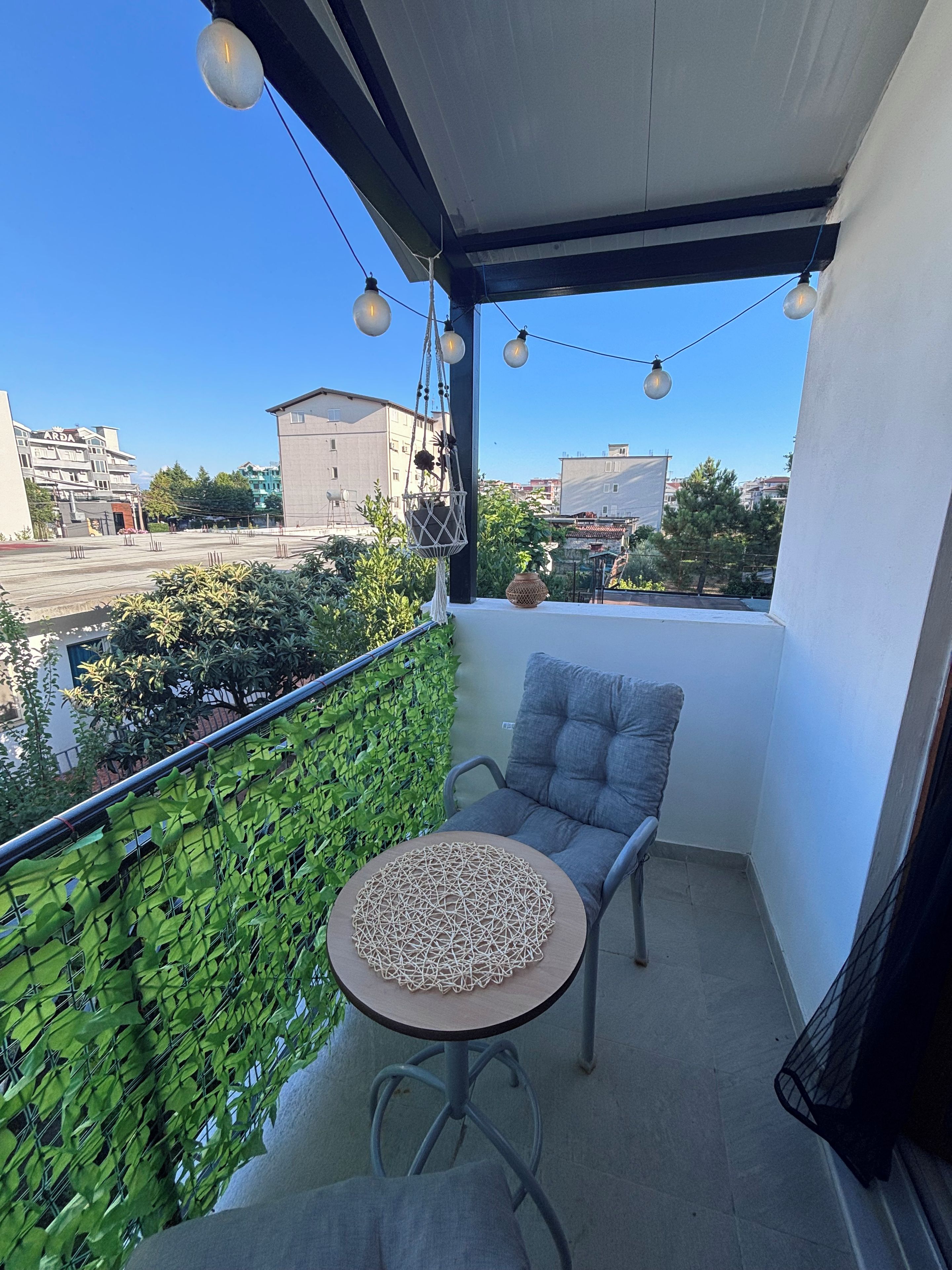 A balcony with a chair, a small table, and a string of lights.