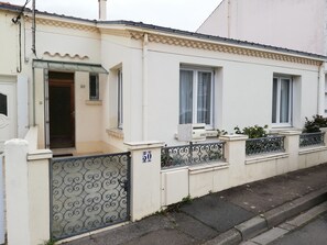 Un bâtiment blanc doté d’un balcon, d’une enseigne portant le numéro « 50 » et d’un portail en métal.