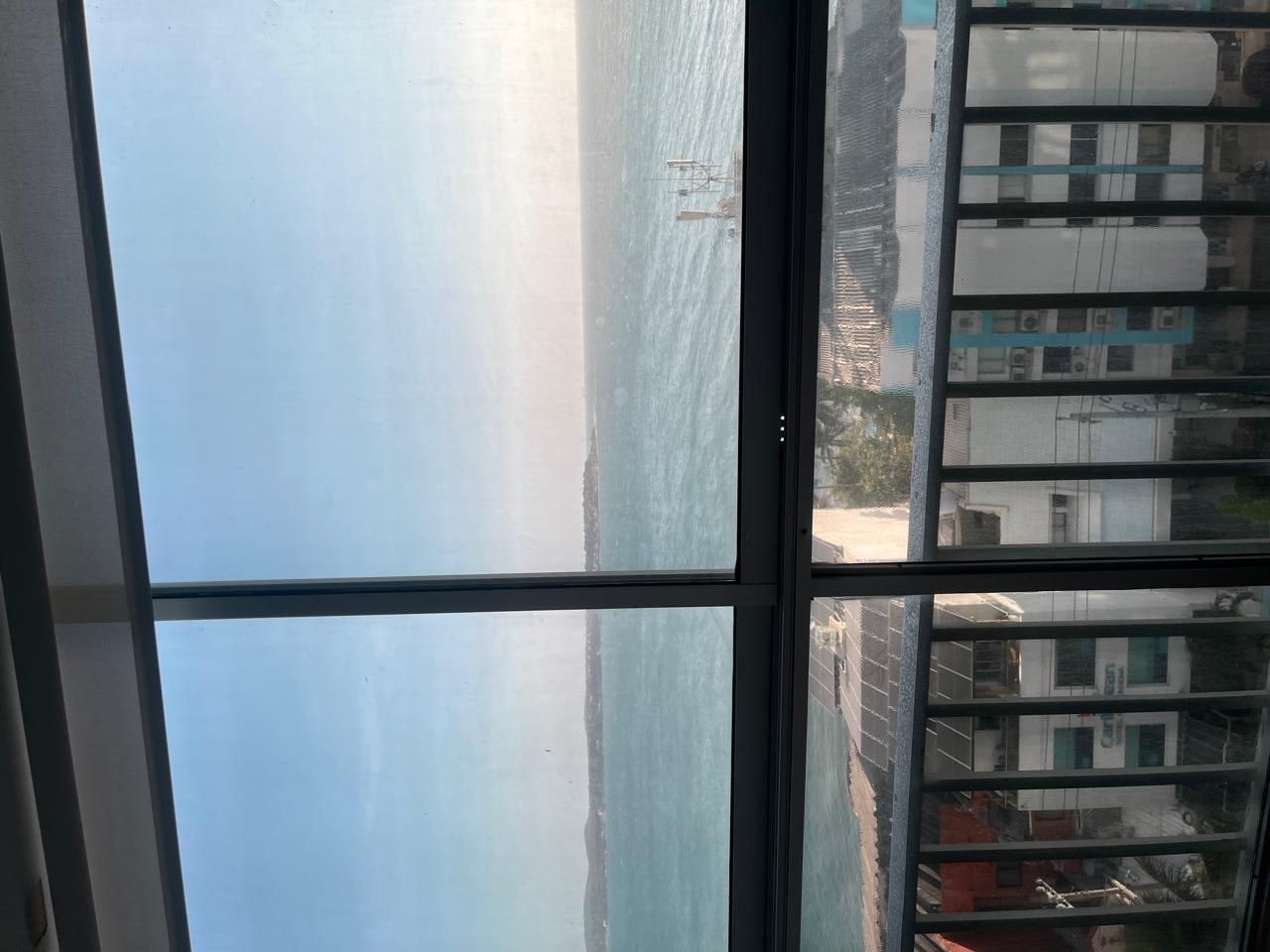 A view through a window with a clear sky and a distant shoreline.