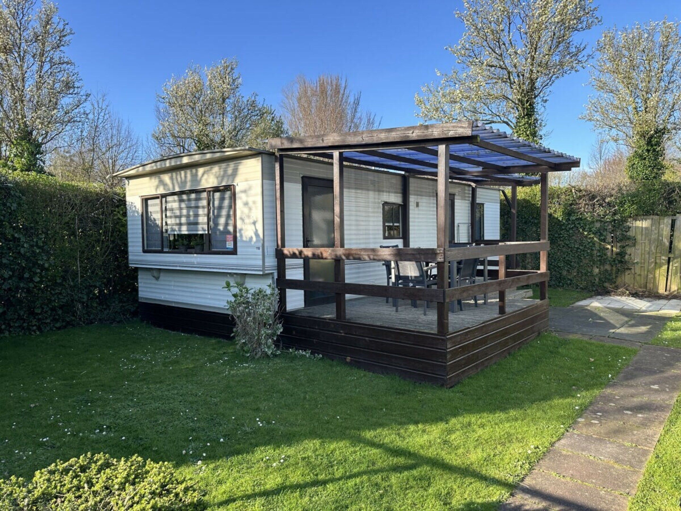 A mobile home with a covered porch and a fenced yard.