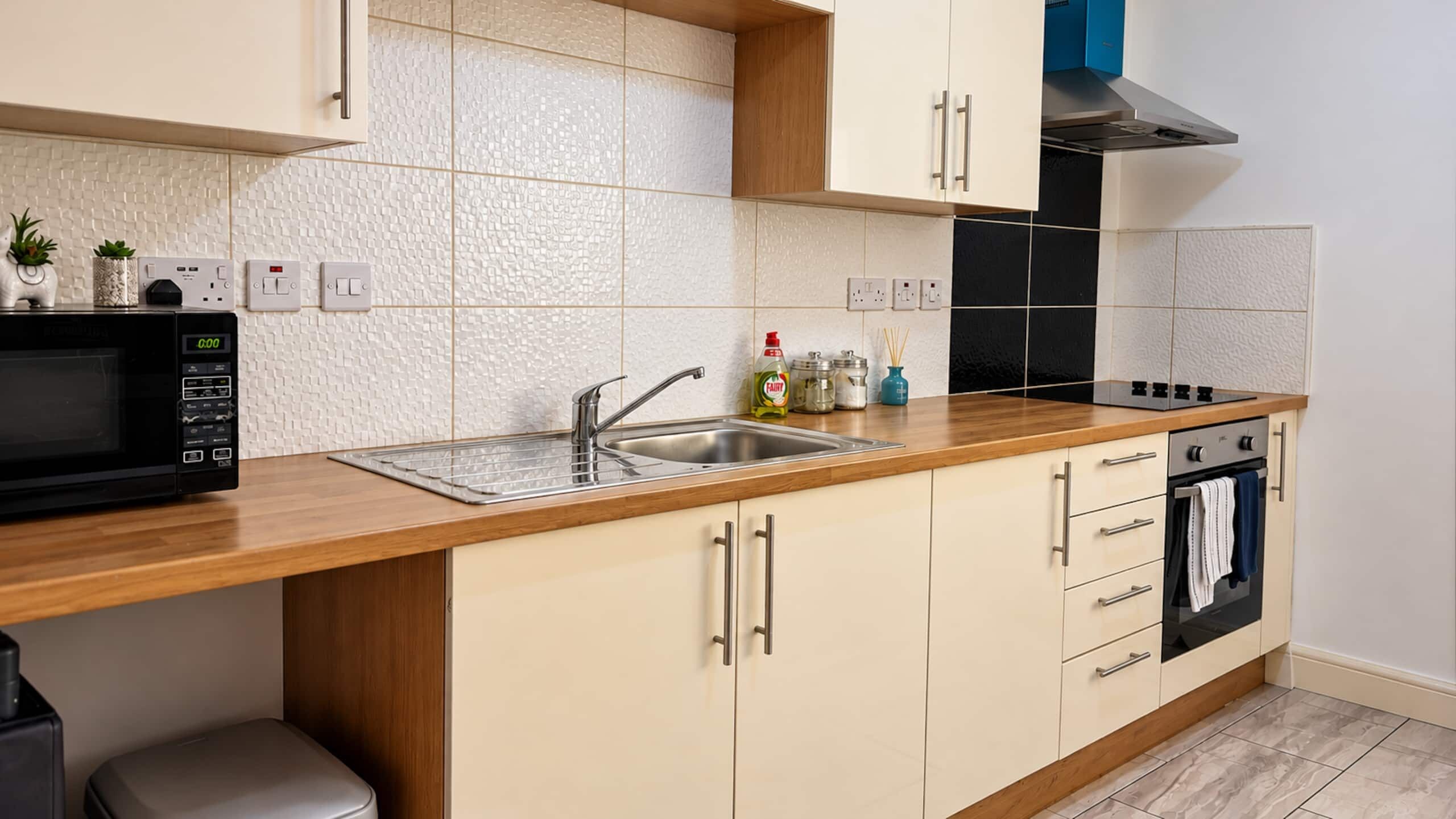 A modern kitchen with a microwave, sink, stove, and cabinets.