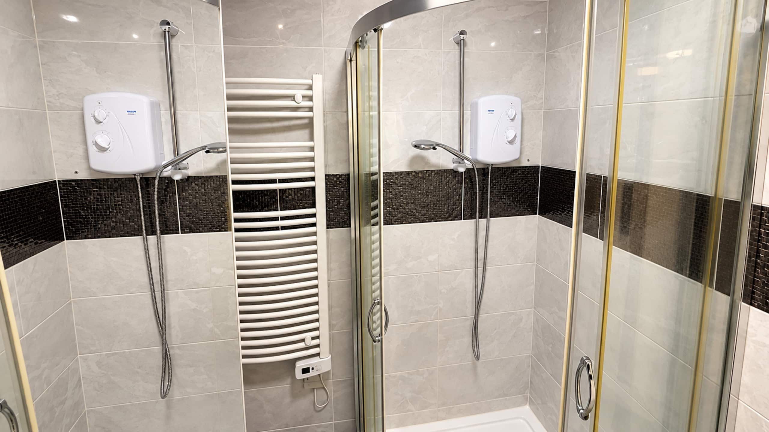 Un baño moderno con cabina de ducha de vidrio, toallero blanco y pared con azulejos blanco y negro.