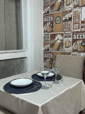 A dining table set with plates, cutlery, and wine glasses, against a wall with a beer-themed wallpaper.
