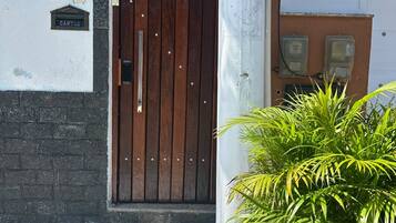 A building entrance with a wooden door, a potted plant, and a sign with the number 70.