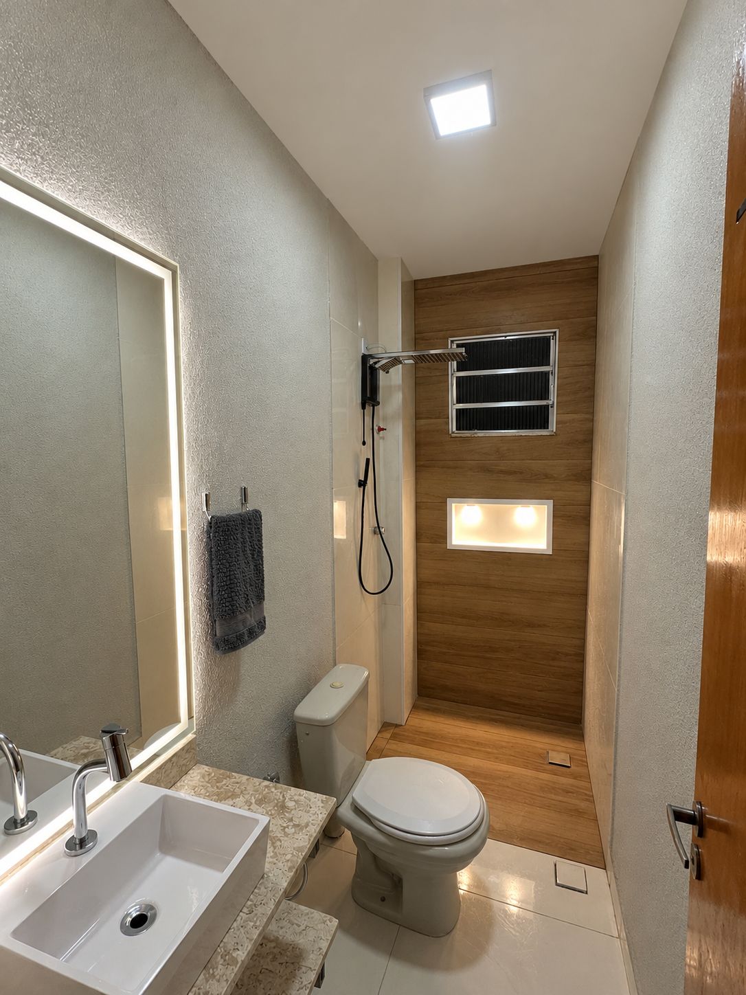 A modern bathroom with a large mirror, a sink, a toilet, and a shower.