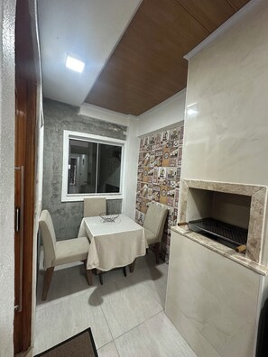 Een kleine kamer met een kitchenette, een eethoek met een tafel en stoelen, een raam en een muur met een ontwerp gebaseerd op bier.
