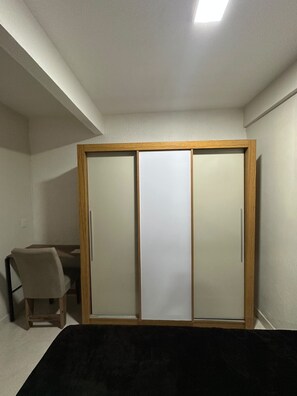 Een kamer met een bed, een bureau en een garderobe met schuifdeuren.