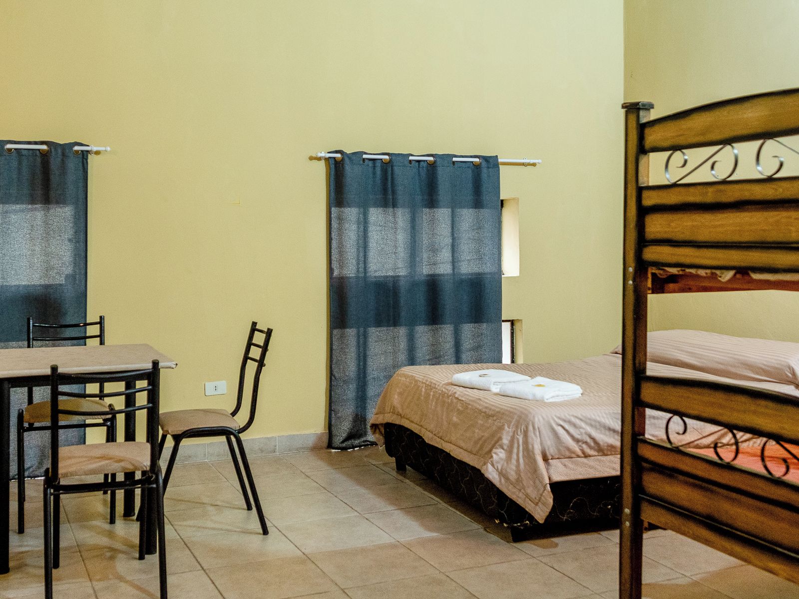 Una habitación con cama, una silla, una mesa y una cortina.