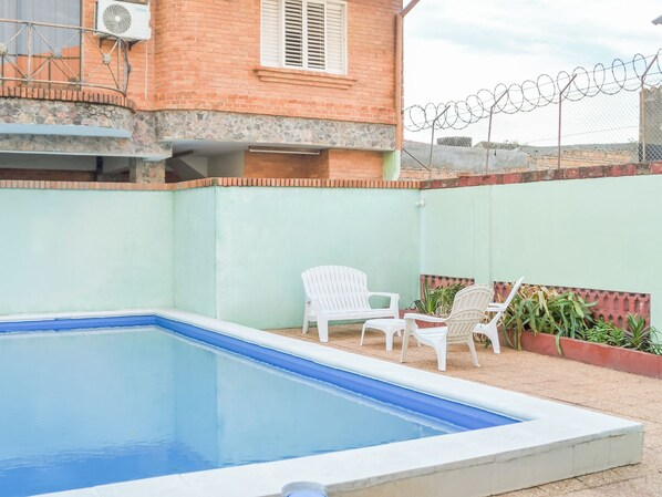 A swimming pool with a brick wall and a barbed wire fence in the background. - Patagonia Hostel (Asunción)