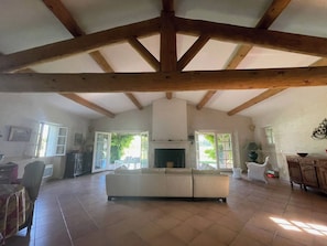 A spacious living room with a high ceiling, a fireplace, and a large sofa.